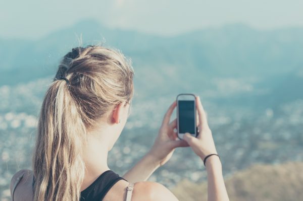 街コンレポート＿女性が高台から景色を携帯電話で撮影しています
