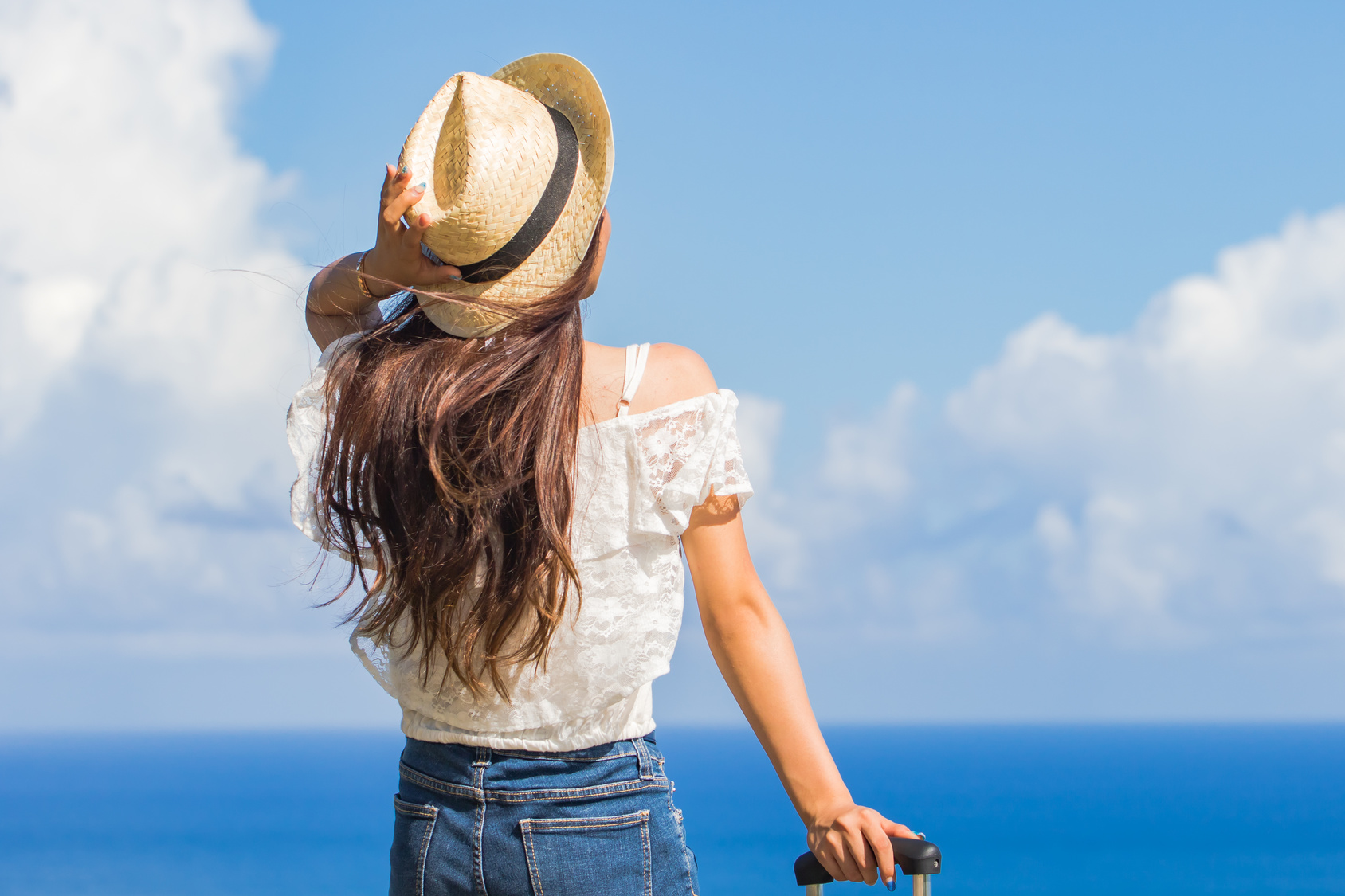 街コンレポート＿海で麦わら帽子を抑えて遠くを見つめる女性