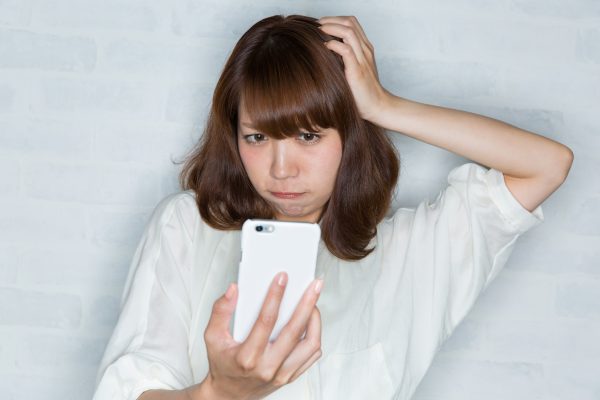 街コンレポート＿携帯電話を見ながら頭を抱えている女性