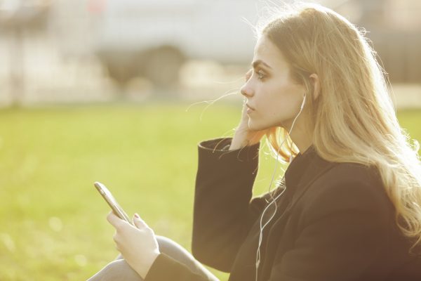 街コンレポート＿女性がイヤホンで音楽を聞いています